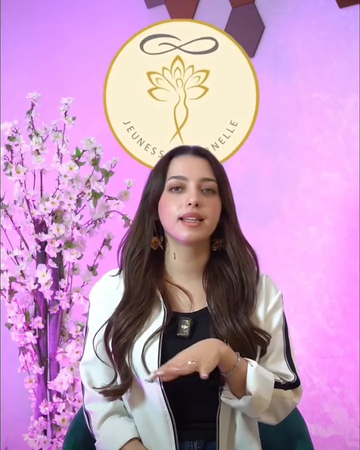La fondatrice assise devant le logo du centre, elle explique en faisant un geste de la main